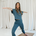 Female model wearing the Bamboo Flex Women’s Leggings in Atlantic and matching short sleeve tee doing a yoga pose