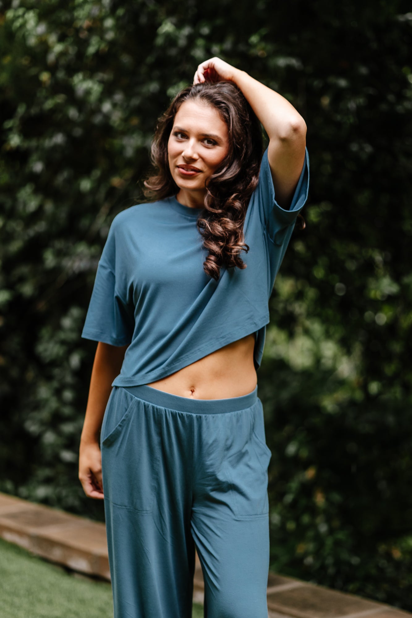 Model standing outside while wearing the Women's Short Sleeve Tee in Atlantic and matching wide leg pants