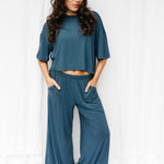 Female model standing in front of a white backdrop wearing the Women's Wide Leg Pant in Atlantic and matching Short Sleeve Tee