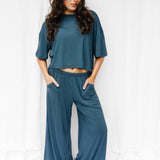 Female model standing in front of a white backdrop wearing the Women's Wide Leg Pant in Atlantic and matching Short Sleeve Tee