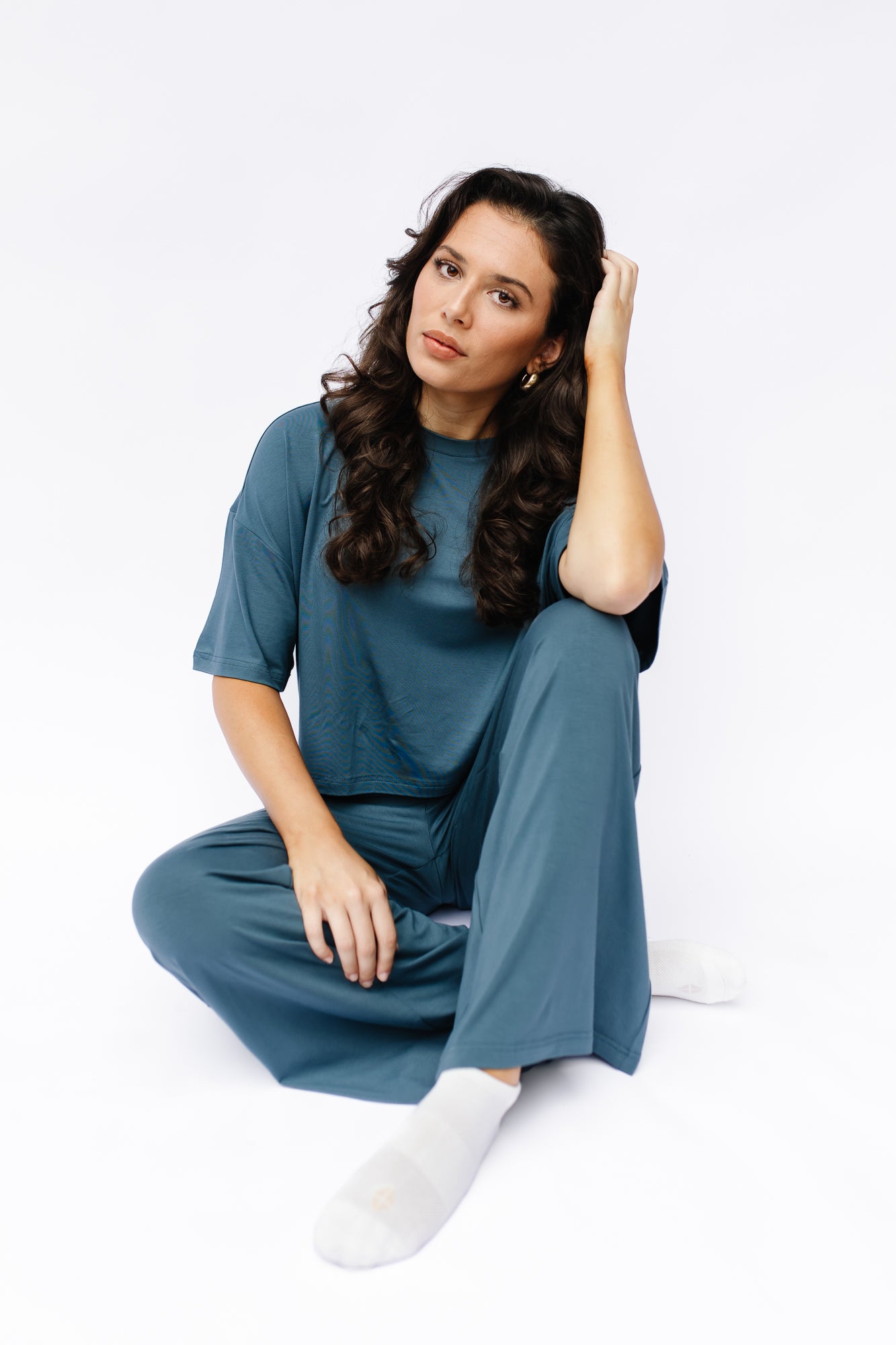 Female model sitting on the floor wearing the Women's Short Sleeve Tee in Atlantic with matching wide leg pants