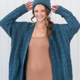 Model wearing the Chunky Cable Knit Cardigan in Atlantic, matching beanie and ribbed cami dress in Latte