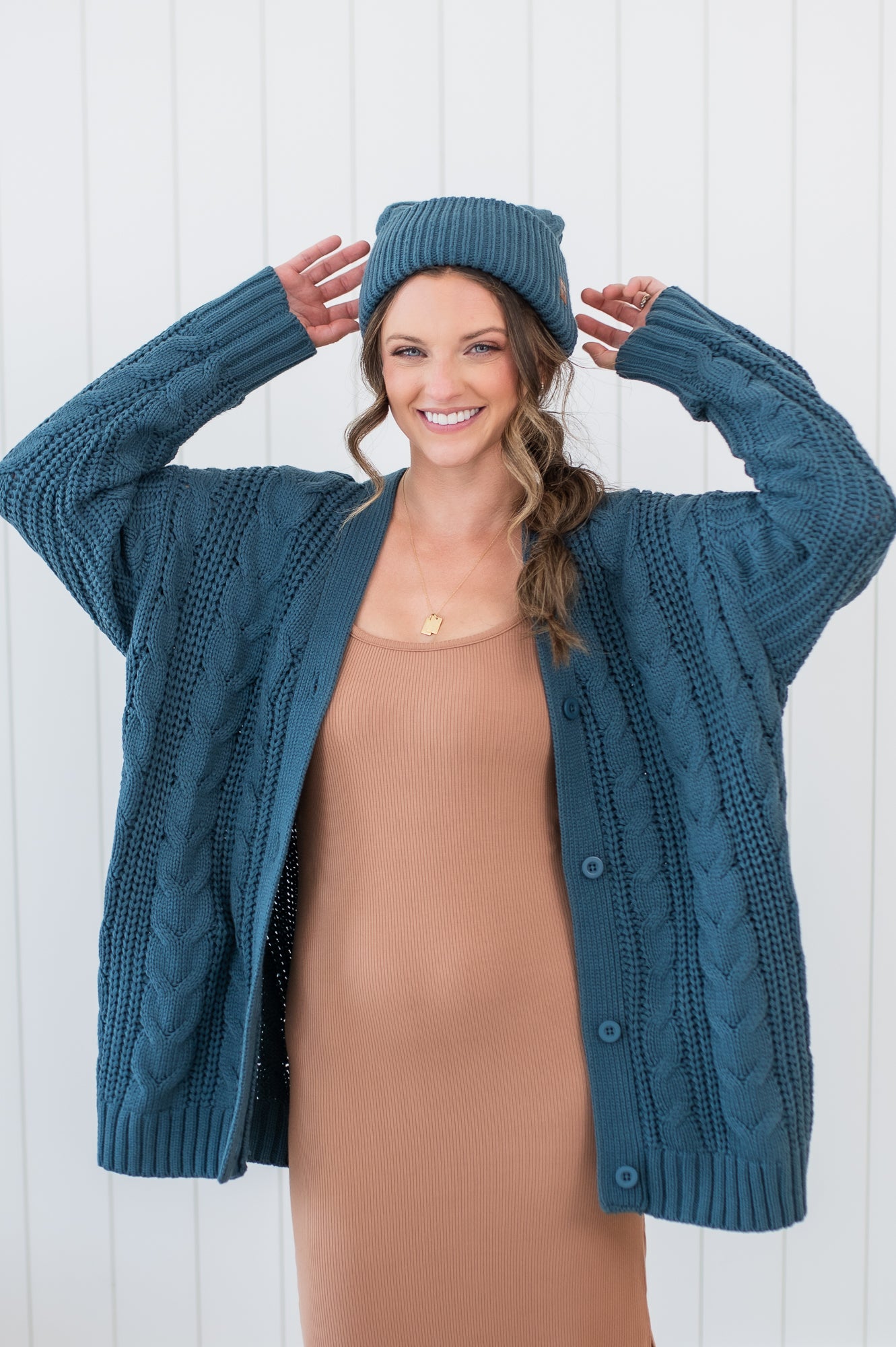 Model wearing the Chunky Cable Knit Cardigan in Atlantic, matching beanie and ribbed cami dress in Latte