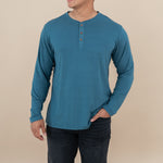 Model wearing the Long Sleeve Henley in Atlantic with dark jeans and one hand in pocket