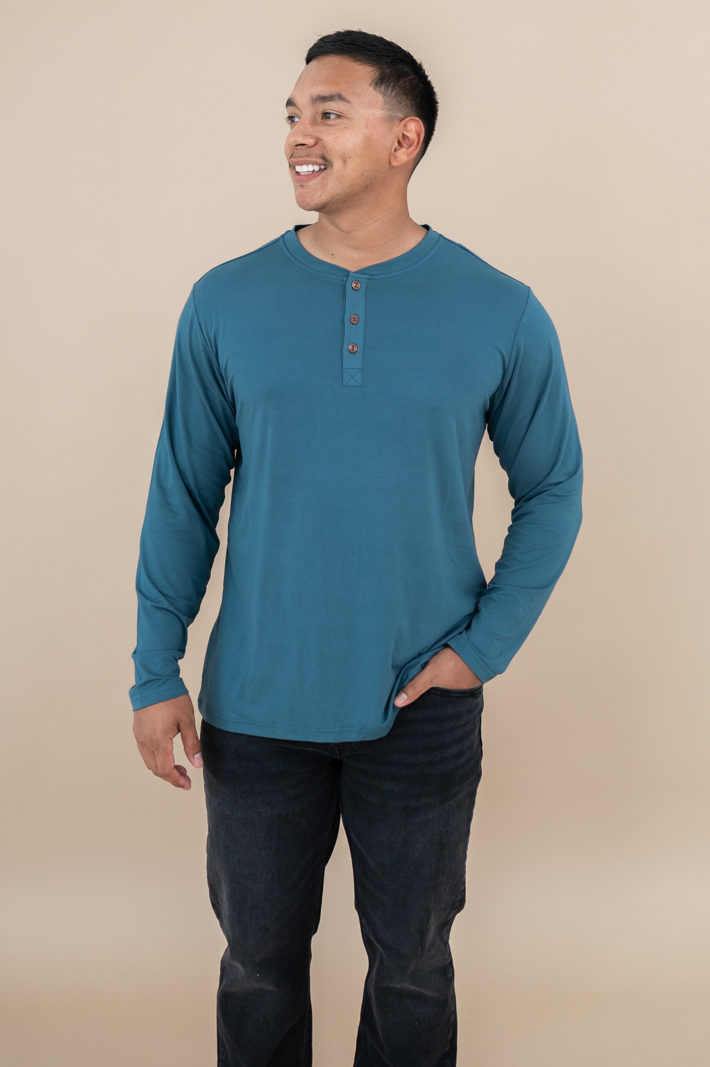 Model wearing the Long Sleeve Henley in Atlantic with dark jeans and one hand in pocket