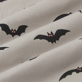 An all-over print featuring the silhouettes of various flying bats with orange eyes over a light tan background color called Khaki. ---1605 1