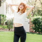 Model standing in a yard with arms up wearing the Kyte Bamboo Flex High Rise Biker Short in Midnight paired with the Bamboo Flex Cloud Baby Tee ::: Model is 5'6" wearing size XS ///

