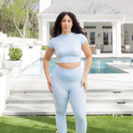 Woman posing in front of a pool wearing the Bamboo Flex Baby Tee in Breeze with matching bamboo flex leggings
