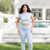 Woman posing in front of a pool wearing the Bamboo Flex Baby Tee in Breeze with matching bamboo flex leggings
