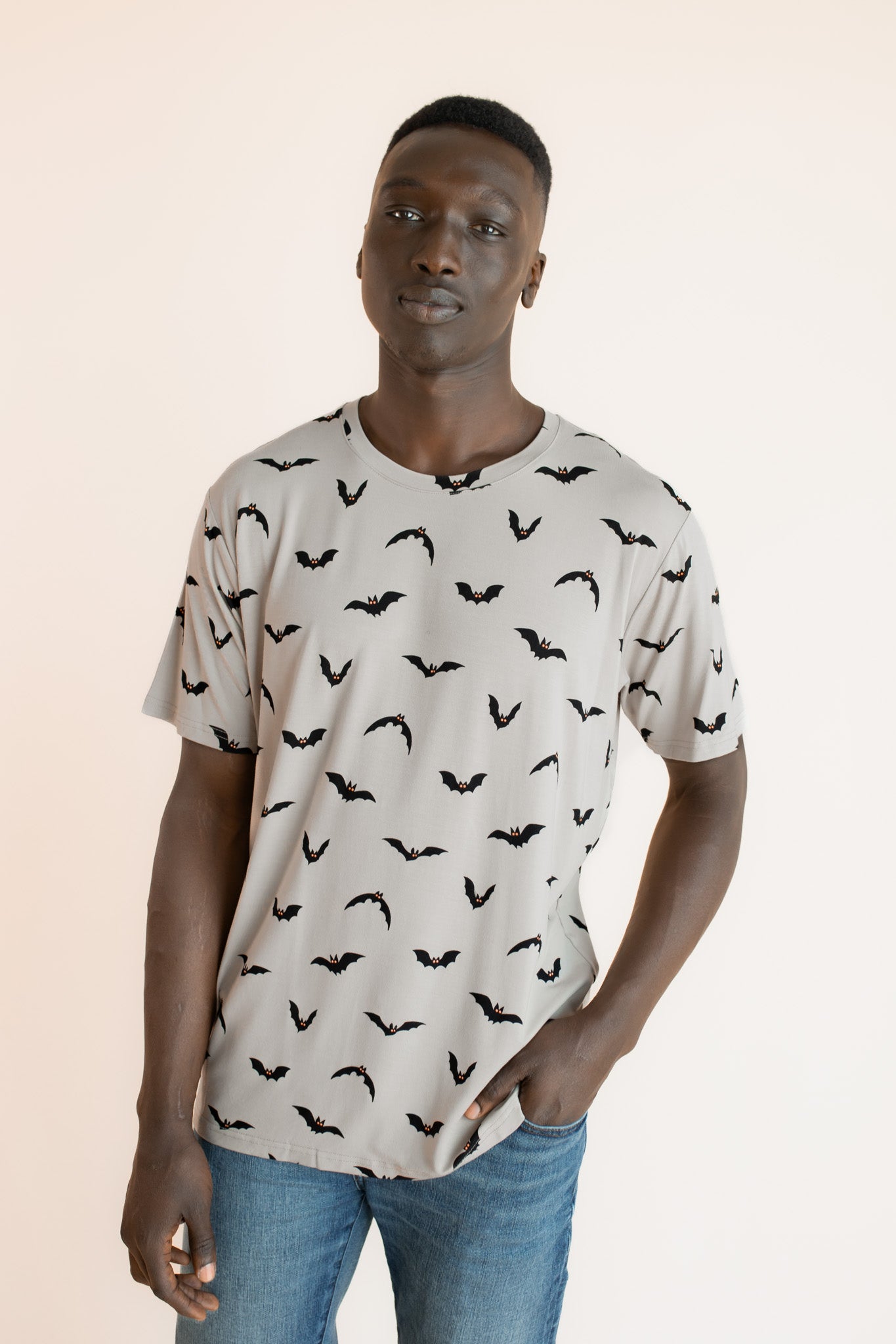 Modal wearing Men's Crew Neck Tee in Bats print over blue jeans on a beige background 