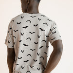 Back side of Modal wearing Men's Crew Neck Tee in Bats print over blue jeans on a beige background