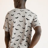 Back side of Modal wearing Men's Crew Neck Tee in Bats print over blue jeans on a beige background
