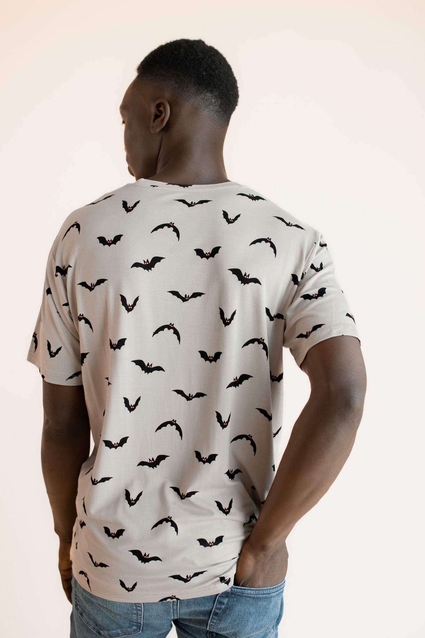 Back side of Modal wearing Men's Crew Neck Tee in Bats print over blue jeans on a beige background