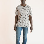 Modal posing in Men's Crew Neck Tee in Bats print over blue jeans on a beige background