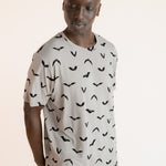 Modal wearing Men's Crew Neck Tee in Bats print over blue jeans on a beige background