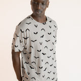 Modal wearing Men's Crew Neck Tee in Bats print over blue jeans on a beige background