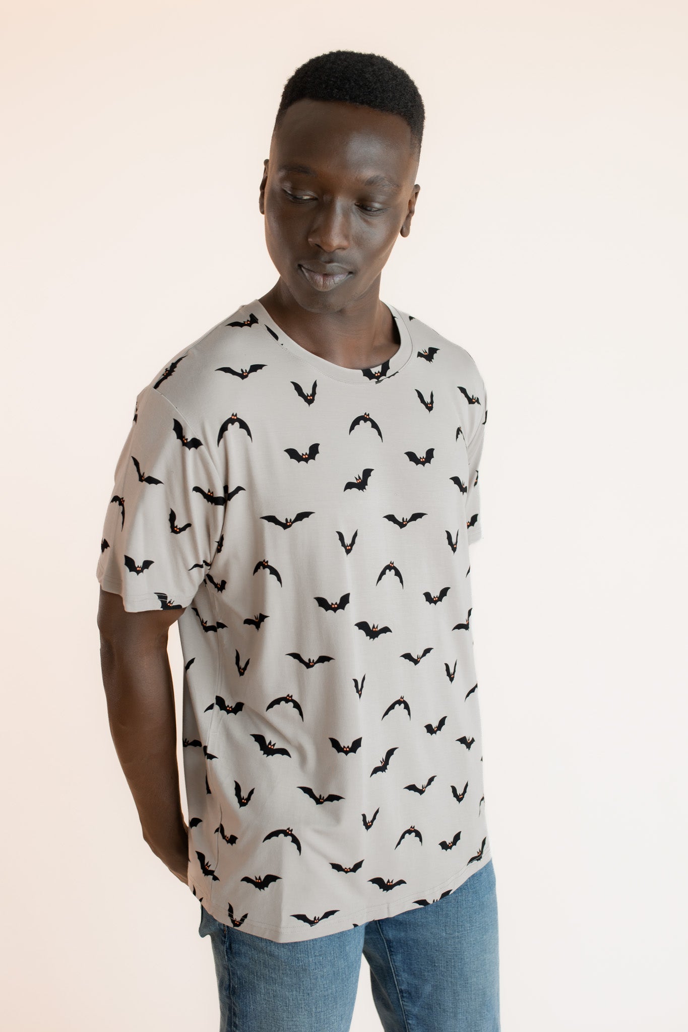 Modal wearing Men's Crew Neck Tee in Bats print over blue jeans on a beige background