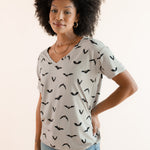Modal posing in Women's Oversized V-Neck Tee in Bats print over light blue jeans on a beige background