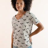 Modal posing in Women's Oversized V-Neck Tee in Bats print over light blue jeans on a beige background