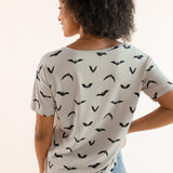 Back side of Modal wearing Women's Oversized V-Neck Tee in Bats print over light blue jeans on a beige background