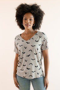 Modal wearing Women's Oversized V-Neck Tee in Bats print over light blue jeans on a beige background