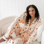 Sitting model with hand on her head wearing the Kyte Women's Long Sleeve Pajama Set in Bewitched