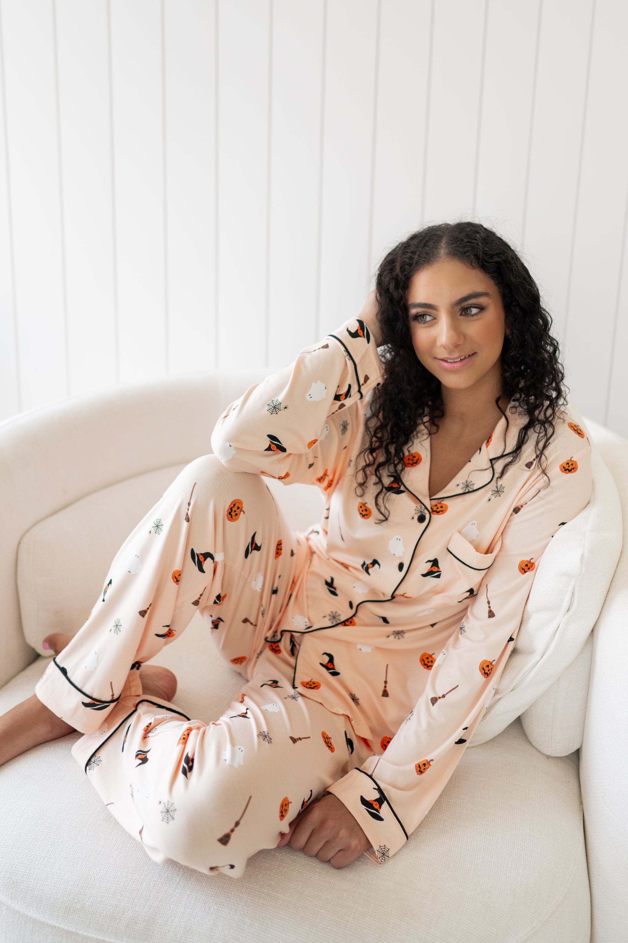Sitting model with hand on her head wearing the Kyte Women's Long Sleeve Pajama Set in Bewitched