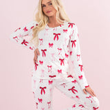 Model standing with one leg up and one arm on hip while wearing the Kyte Bamboo Women's Jogger Pajama Set in Big Love Bow