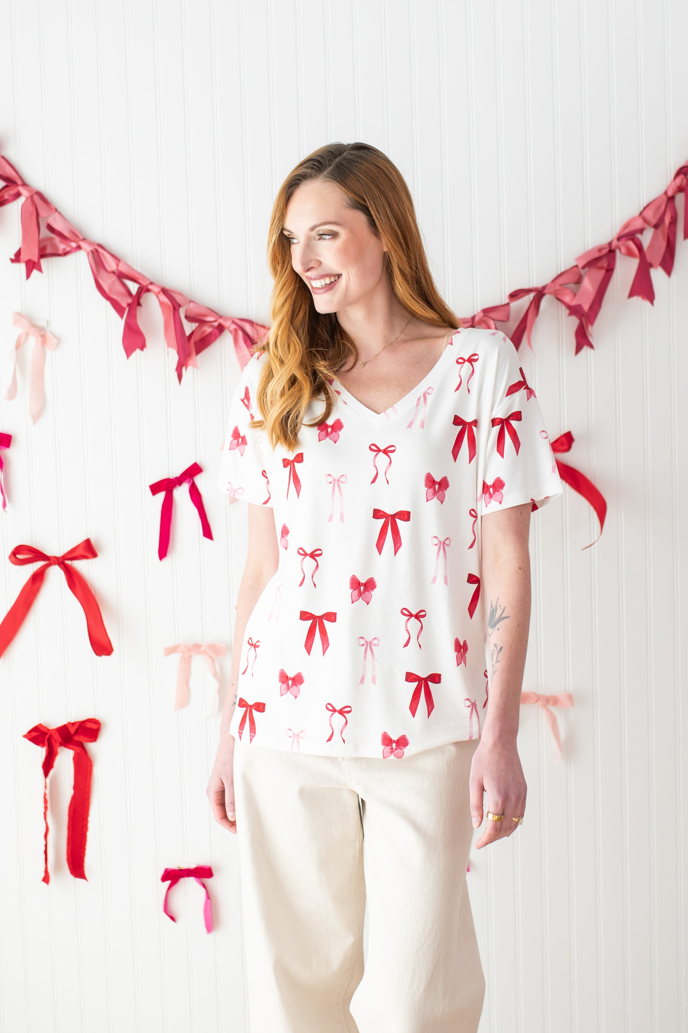 Model smiling to the side while wearing the Kyte Bamboo Women's Relaxed Fit V-Neck in Big Love Bow