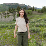 Smiling model wearing the Woman's Crew Neck in Bisque in a green field
