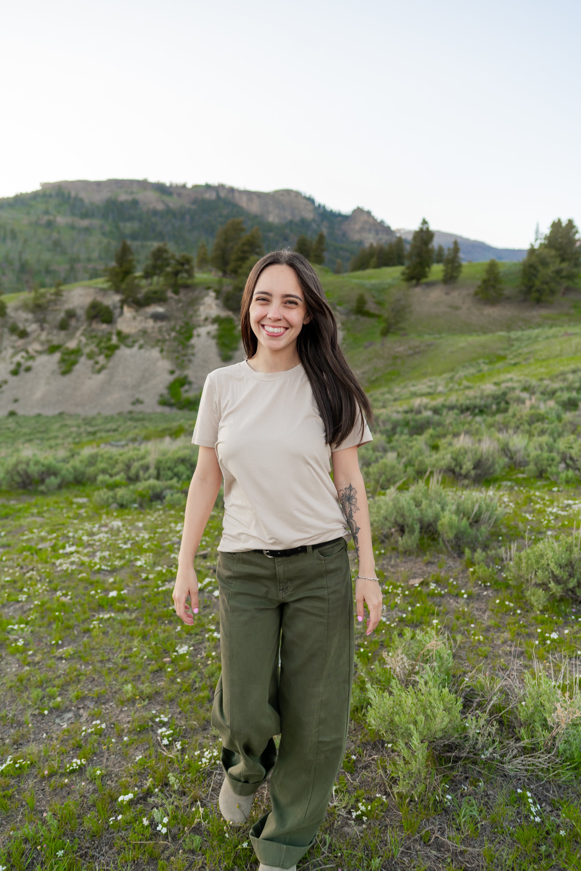 Smiling model wearing the Woman's Crew Neck in Bisque in a green field