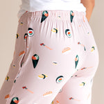 Back side of pink Women's Lounge Pants in Sushi print under white camisole on a beige background