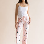 Model posing in pink Women's Lounge Pants in Sushi print under white camisole on a beige background