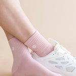 Pink socks with kite designs worn with white sneakers on a beige background