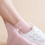 Pink socks with kite designs worn with white sneakers on a beige background