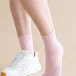 Person wearing pink socks and white sneakers on a beige background