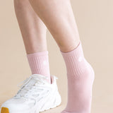 Person wearing pink socks and white sneakers on a beige background