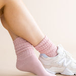 Person wearing pink socks and white sneakers on a light background
