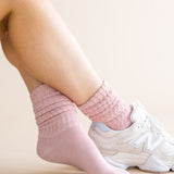Person wearing pink socks and white sneakers on a light background