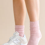 Person wearing pink socks and white sneakers on a beige background