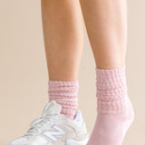 Person wearing pink socks and white sneakers on a beige background