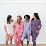 Group of 4 women modeling Kyte Living loungewear and pajamas in pink and purple hues