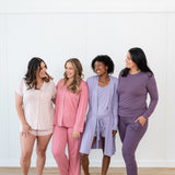 Group of 4 women modeling Kyte Living loungewear and pajamas in pink and purple hues