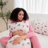 Woman in apple blossom pajamas modeling with Standard Pillowcase in Blush Butterfly on a bed 