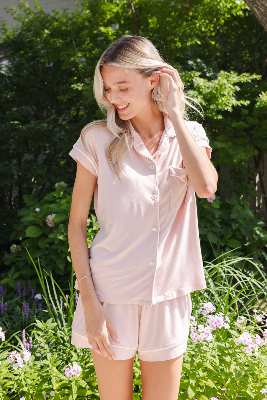 Woman outside looking over her shoulder in blush colored short sleeve pajamas.