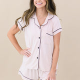 Woman modeling Women’s Short Sleeve Pajama Set in Blush with Midnight Trim. Hand on hip and smiling off to the side of camera