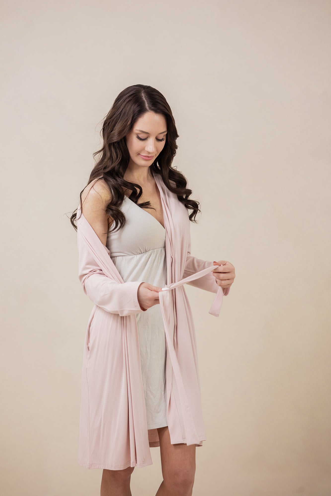 Model looking down while wearing the Kyte Women's Robe in Blush