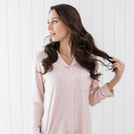Woman looking to the side with hand in hair while modeling the Kyte Long Sleeve Women's Pajama Set in Blush with Cloud Trim 