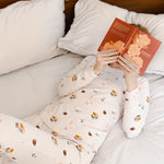 Modal lying on bed wearing Women's Jogger Pajama Set in Book Club print reading a book
