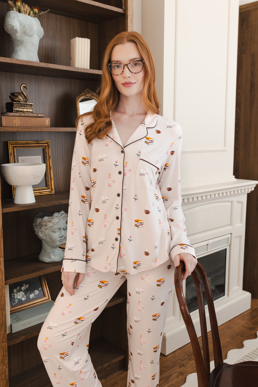 Modal wearing Long-Sleeved Women's Pajama Set in Book Club print posing in a living room